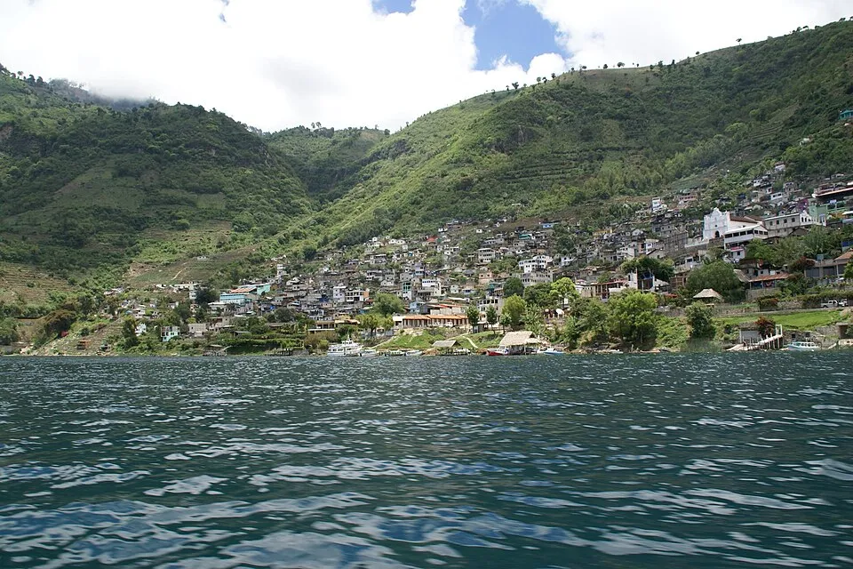 The hillside town of San Antonio Palopo with houses climbing a green slope above Lake Atitlan, seen from the water.