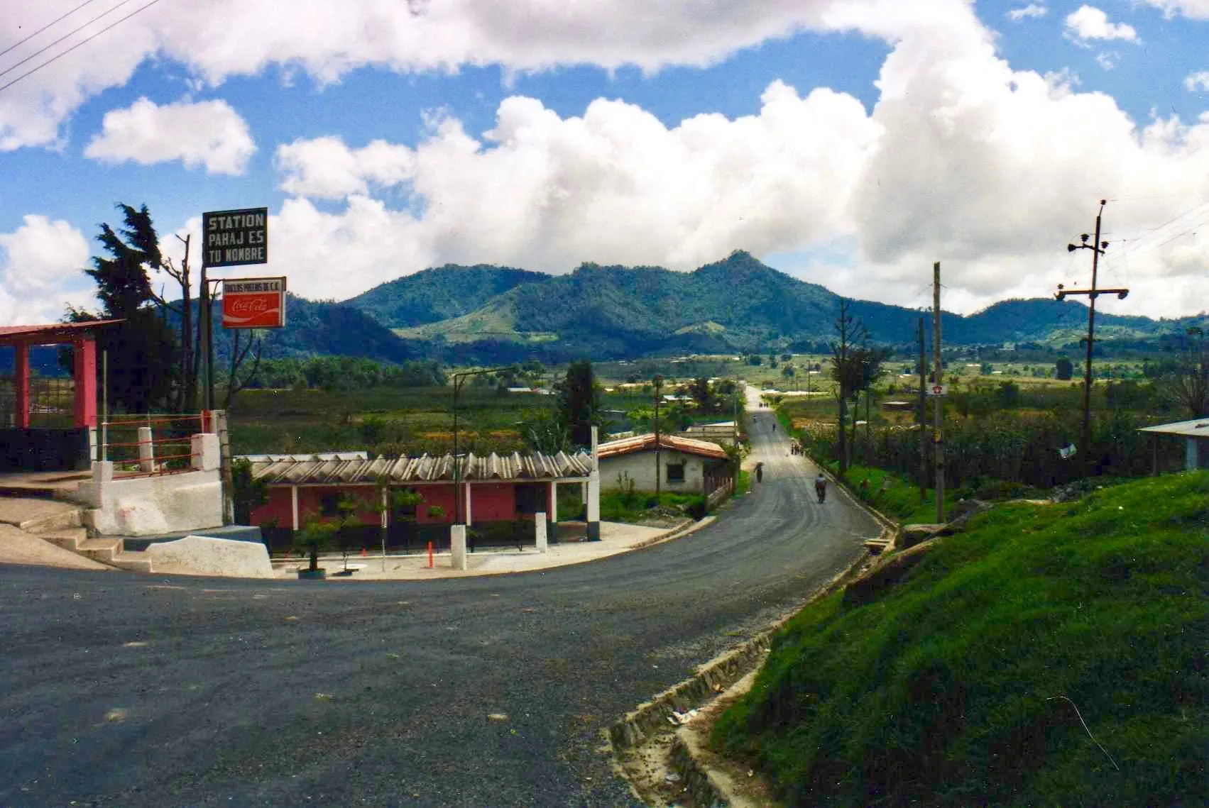A two-lane highway junction in the hills near Solola, with mountains and cornfields in the background.